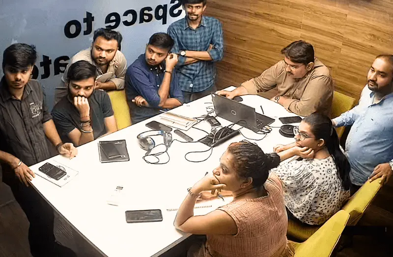 A group of MagnusMinds developer team sits around a table discussing the project