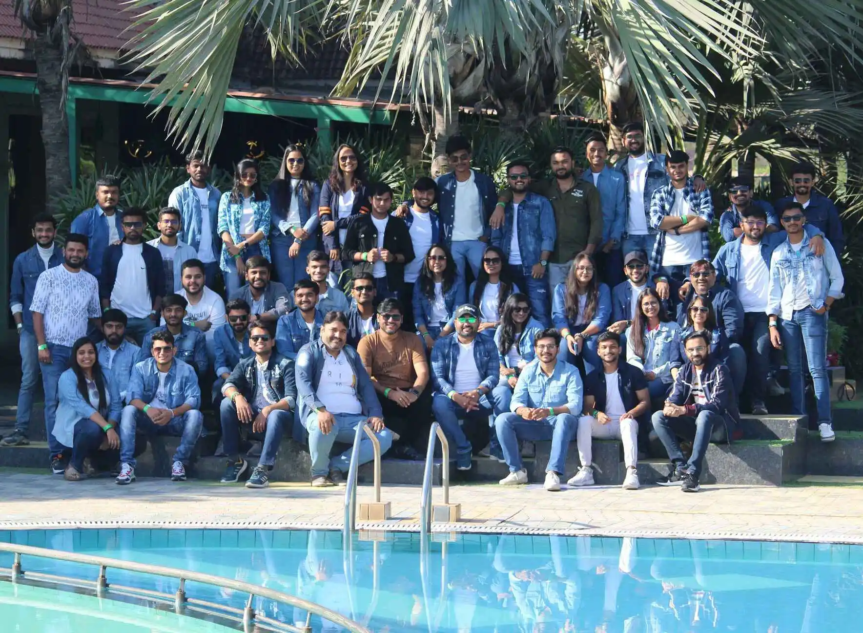 A group of the MagnusMinds developer team sit by the swimming pool and pose for a photo on the tour